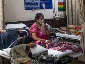 A woman who contracted the coronavirus sits connected to oxygen supply inside the emergency ward of a Covid-19 hospital on May 03, 2021 in New Delhi, India. India recorded more than 360,000 coronavirus cases in a day for the 12th day in a row as the total number of those infected according to Health Ministry data neared 20 million. The real figure could be up to ten times higher, many health experts say, due to a lack of widespread testing or reporting, and only patients who succumbed in hospitals being counted. A new wave of the pandemic has totally overwhelmed the country's healthcare services and has caused crematoriums to operate day and night as the number of victims continues to spiral out of control.