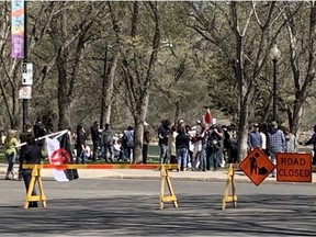 A man carrying a Canadian Nationalist Party flag approaches the crowd gathered for a rally protesting COVID-19 public health orders. (Bryn Levy/Saskatoon StarPhoenix)