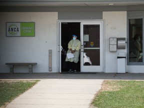 A vaccine clinic worker stands at the door, waiting for people to arrive to a walk-in COVID-19 vaccine clinic at the Argyle North Community Association community centre in Regina, Saskatchewan on May 13, 2021.