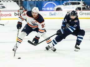 Edmonton Oilers forward Connor McDavid (97) skates away from Winnipeg Jets forward Nate Thompson (11) during the first period in game four of the first round of the 2021 Stanley Cup Playoffs at Bell MTS Place.