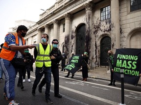 A police officer detains an activist from the Extinction Rebellion, a global environmental movement, during a protest outside the Bank of England building, in London, Britain, April 1, 2021.