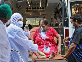 Health-care workers and relatives carry a woman from an ambulance for treatment at a COVID-19 care facility, amidst the spread of COVID-19 in Mumbai, India, May 4, 2021.