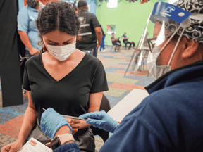 A healthcare worker prepares to give a woman a COVID-19 vaccine shot at a mobile vaccine clinic in Pasadena, Texas.