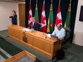 Saskatchewan Premier Scott Moe, centre, and Saskatchewan's chief medical health officer, Dr. Saqib Shahab, right, speak to members of the media during a press conference held at the Saskatchewan Legislative Building in Regina, Saskatchewan on August 17, 2020. ASL interpreter Karen Nurkowski is seen on the left. BRANDON HARDER/ Regina Leader-Post