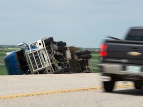 A vehicle drives past a semi rolled on its side in the ditch next to near the exit ramp leading to Balgonie, Saskatchewan on June 10, 2021. The semi flipped amid high winds in the Regina area, with gusts peaking that morning around 70 to 80 km-h.