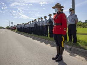 RCMP, Regina Police Service, Regina Fire & Protective Services, EMS, Highway Patrol and Fill Hills Police, along with other emergency service members, watch a procession of police vehicles following a hearse down Dewdney Avenue in Regina on June 15, 2021. The procession passed by RCMP 'F' Division headquarters to honour RCMP Const. Shelby Patton, who died in the line of duty in Wolseley, Sask. TROY FLEECE / Regina Leader-Post