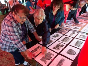 MUSKOWEKWAN FIRST NATION, SASK : June 22, 2021  -- From left, Joan Manitopyes, Rose Young, and Doreen Smoke look at archival photos of the former Muscowequan Indian Residential School on the school's grounds on Muskowekwan First Nation in Saskatchewan on June 22, 2021. Young can be seen pointing to herself in a photo as a student of the school in 1946. The photos were brought in for an event during which it was announced $4.88M has been earmarked for research knowledge gathering and initial ceremonies related to the burial sites of children who never returned from residential schools in Saskatchewan.

BRANDON HARDER/ Regina Leader-Post