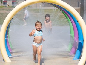 Annalin and Luca Lamb run through the rings at a spray park to cool down in this hot Saskatoon summer weather.