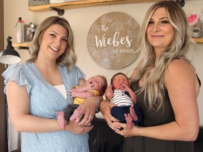 Sisters Liz Connolly and Alyssa Wiebe poses for a photo with newborns Tate and Wyatt. The pair of sisters ended up delivering both babies within hours of one another.
