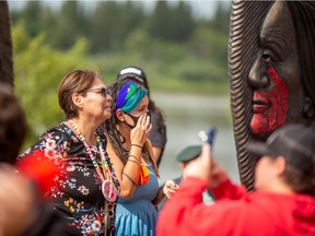 Artist Tristen Sanderson, in blue, looks at the Sisters in Spirit memorial, a sculpture to honour murdered and missing Indigenous women and children created by Sanderson and Lionel Peyachew. Photo taken in Prince Albert, SK on Wednesday, July 7, 2021.