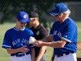 Blue Jays head coach Grant Scheirich presents Dustin Mercier with a signed baseball from the whole team, honouring him after his injury a month ago — when he suffered multiple fractures after taking a hard-hit baseball to his eye. Photo taken in Saskatoon on July 12, 2021.