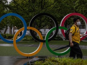 A man wearing a face mask walks past the Olympic Rings on July 8, 2021 in Tokyo, Japan.