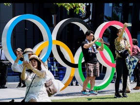 People take selfies in front of an Olympic Rings monument near the National Stadium, the main venue of Tokyo 2020 Olympics and Paralympics in Tokyo, Japan, July 19, 2021. REUTERS/Naoki Ogura ORG XMIT: GGGTOK003