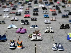 Dried flowers rest inside a pair of child's running shoes at a memorial for the 215 children whose remains were found at the grounds of the former Kamloops Indian Residential School at Tk’emlups te Secwépemc First Nation in Kamloops, B.C., on Parliament Hill in Ottawa on Friday, June 4, 2021.