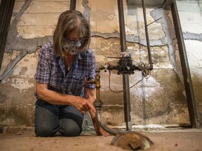 Kathy Donovan, a Cathedral residents with major concerns about the City of Regina's approach to lead service connections, points to a white scratch mark that she believes identifies her pipe to being made of lead on Wednesday, July 28, 2021 in Regina.