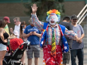 Doodoo the clown waves to people lined up on opening day of the Saskatoon Ex.