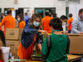 Volunteers and staff at White Buffalo Youth Lodge pack school supplies into backpacks for children at the seventh annual backpack giveaway. The event also featured a COVID-19 vaccine pop-up, free haircuts, cleaning supplies and food.