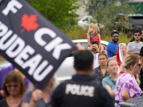 Protestors wave flags and chant as Prime Minister Justin Trudeau speaks during a Liberal campaign event at VeriForm Inc. in Cambridge, Ontario, on August 29, 2021.