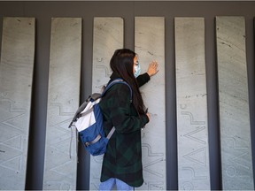 A University of Saskatchewan student feels the grooves on a new art installation at the Gordon Snelgrove Gallery where 13 of the old stone steps from the Thorvaldson building have been reclaimed, and carved with Cree syllabics to highlight the 13 moons of the lunar cycle, as part of the anohc kipasikonaw/we rise/niipawi art project. Photo taken in Saskatoon, Sept. 21, 2021.