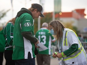 An attendant checks COVID-19 vaccination status of ticketholders prior to a CFL football game between the Saskatchewan Roughriders and the Toronto Argonauts at the entrance to Mosaic Stadium on Friday. BRANDON HARDER/ Regina Leader-Post