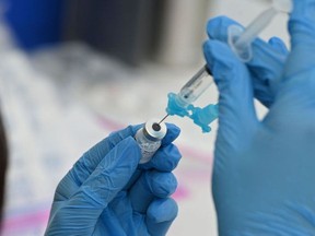 In this file photo a health-care worker fills a syringe with Pfizer COVID-19 vaccine at a community vaccination event in Los Angeles, Aug. 11, 2021.
