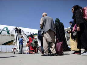 Passengers stand in a queue to board on a Pakistan International Airlines plane, which is the first international commercial flight to land since the Taliban retook power in Afghanistan on August 15, at the airport in Kabul on September 13, 2021.