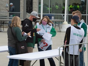 Attendants check COVID-19 vaccination status of ticketholders prior to a CFL football game between the Saskatchewan Rougriders and the Toronto Argonauts at the entrance to Mosaic Stadium in Regina, Saskatchewan on Sept. 17, 2021.