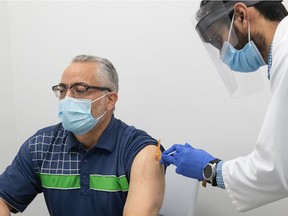 Ahmed Aboudheir, president of the Regina section of the Islamic Association of Saskatchewan, gets his second dose of COVID-19 vaccine from Greens Pharmacy owner and manager Jeet Patel at the pharmacy in Regina, Saskatchewan on June 11, 2021.