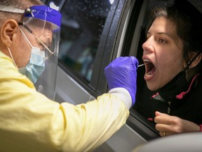 Carine Perrier receives a COVID-19 test from Francois Provost at the new drive-thru testing clinic at the Olympic stadium on Tuesday October 20, 2020 during the COVID-19 pandemic.