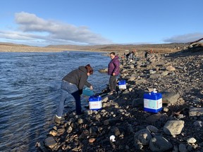Residents collect water from the Sylvia Grinnell River near Iqaluit, Nunavut on Wednesday, Oct. 13, 2021 after potential petroleum was discovered in the city's tap water, making it undrinkable.