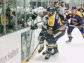 Saskatchewan Huskies forward Owen Hardy battles with Trinity Western Spartans defence Travis Verveda during first period Canada West hockey action in Saskatoon on Nov. 12, 2021.