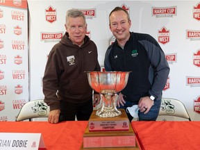 Manitoba Bisons head coach Brian Dobie and Huskies head coach Scott Flory stand for a photo with the Hardy Cup during a press conference in advance of their Saturday conference football championship game.