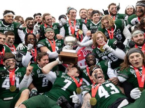 Huskies players celebrate with the Hardy Cup after beating Manitoba in Saturday's Canada West football final.