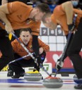 Saskatoon SK,November 28, 2021.Tim Hortons Curling Trials.Skip Brad Gushue sits in the rings as (L-R) 2nd.Brett Gallant and lead Geoff Walker bring the stone into the house during mens final agains team Jacobs.Curling Canada/ Michael Burns Photo
