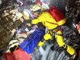 The injured man lies in the blue stretcher as rescuers carefully traverse fast-flowing rivers and slippery surfaces.