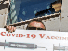 Healthcare workers watch from above as people gather outside Toronto General Hospital to protest against COVID-19 vaccines and COVID-19 related restrictions, September 13, 2021.