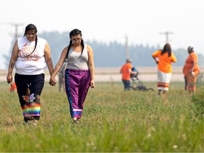 Storm and Lacy Night, whose grandparents attended the Delmas Indian residential school, hold hands as they walk across the ground where the search for potential unmarked graves begins. Photo taken in Delmas, July 17, 2021.