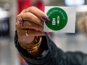 A woman holds up a sticker that reads "I got my COVID-19 vaccine!" after receiving her first dose in Saskatoon, SK on Friday, April 9, 2021.