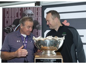 Western head coach Greg Marshall, left, chats with Saskatchewan Huskies' head coach Scott Flory, while standing behind the Vanier Cup trophy on Thursday in Quebec City.