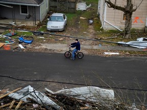 A man rides a bike past debris after a devastating outbreak of tornadoes ripped through several U.S. states in Mayfield, Kentucky, U.S. December 16, 2021. REUTERS/Cheney Orr