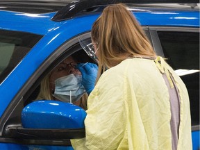 A health worker demonstrates how a COVID-19 swab test is conducted at the Saskatchewan Health Authority drive-thru COVID-19 testing facility in Regina.