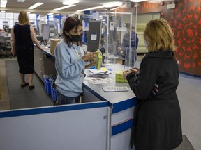 Victoria Scherban, left, public service clerk, hands out a rapid test at the Regina Public Library central branch on Friday, Jan. 14, 2022 in Regina.