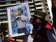 A supporter of Novak Djokovic holds his photo during a rally outside the Park Hotel, where the tennis star is believed to be held while he stays in Australia, in Melbourne, Sunday, Jan. 9, 2022.