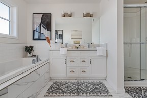 The ensuite in the Waterfront Towns’ Felix model home is elegantly appointed with a quartz-topped double sink vanity, a soaker tub set in a tile-covered deck, a glassed-in walk-in shower and separate toilet closet. SUPPLIED PHOTO