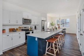 A nine-foot quartz-topped island, painted in rich blue, stands out against the elegant Shaker-style cabinets in the Waterfront Towns’ Felix model home, located at 3037 Brighton Common. Rustic wood grain luxury vinyl plank flooring adds warmth to the kitchen’s crisp white tones. SUPPLIED PHOTO