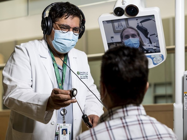  Dr. Ivar Mendez demonstrates the use of a Telehealth robot with the help of robotics engineer coordinator Luis Bustamante (seated) and robotics technologist Joseph Deason (on screen).