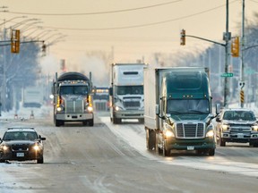 Trucks drive down the road towards the Ambassador Bridge border crossing in Windsor, Ont., on Feb. 14, 2022.