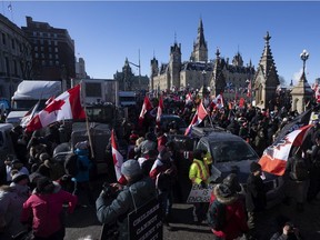 Protestors mingle around vehicles parked on Wellington Street in front of West Block and the Parliament buildings as they participate in a cross-country truck convoy protesting measures taken by authorities to curb the spread of COVID-19 and vaccine mandates in Ottawa on Saturday, Jan. 29, 2022.
