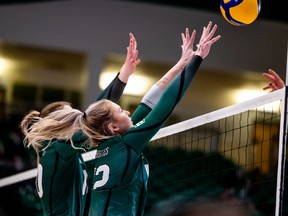 La passeuse des Huskies de l'Université de la Saskatchewan Averie Allard (12) et la milieu Mandi Fraser (10) tentent de bloquer les éliminatoires de volleyball féminin de Canada-Ouest contre les Bisons du Manitoba à Saskatoon le jeudi 3 mars 2022.