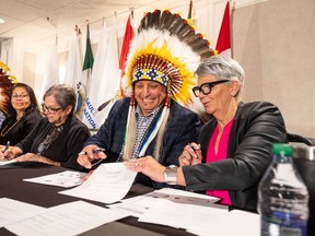 Saskatoon Tribal Council Chief Mark Arcand, centre, and Corrections, Policing and Public Safety Minister Christine Tell, right, sign the Offender Reintegration Partnership Agreement. Photo taken in Saskatoon, SK on Friday, March 4, 2022.